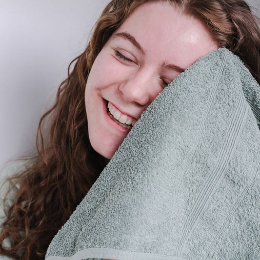 Kvinna torkar sig i ansiktet med en handduk